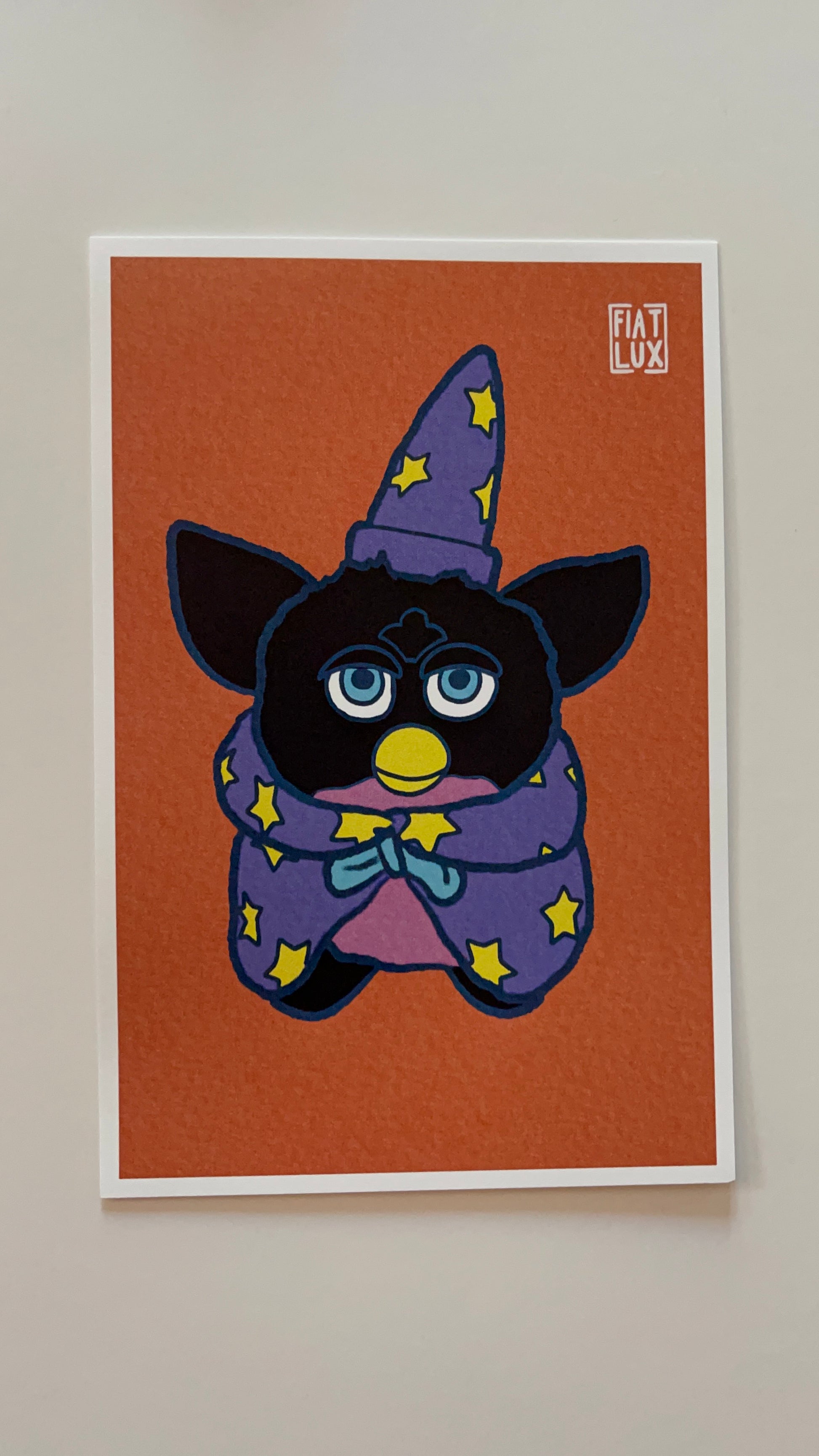 Art print of a furby in a purple wizard hat and cape with yellow stars on a solid orange background.