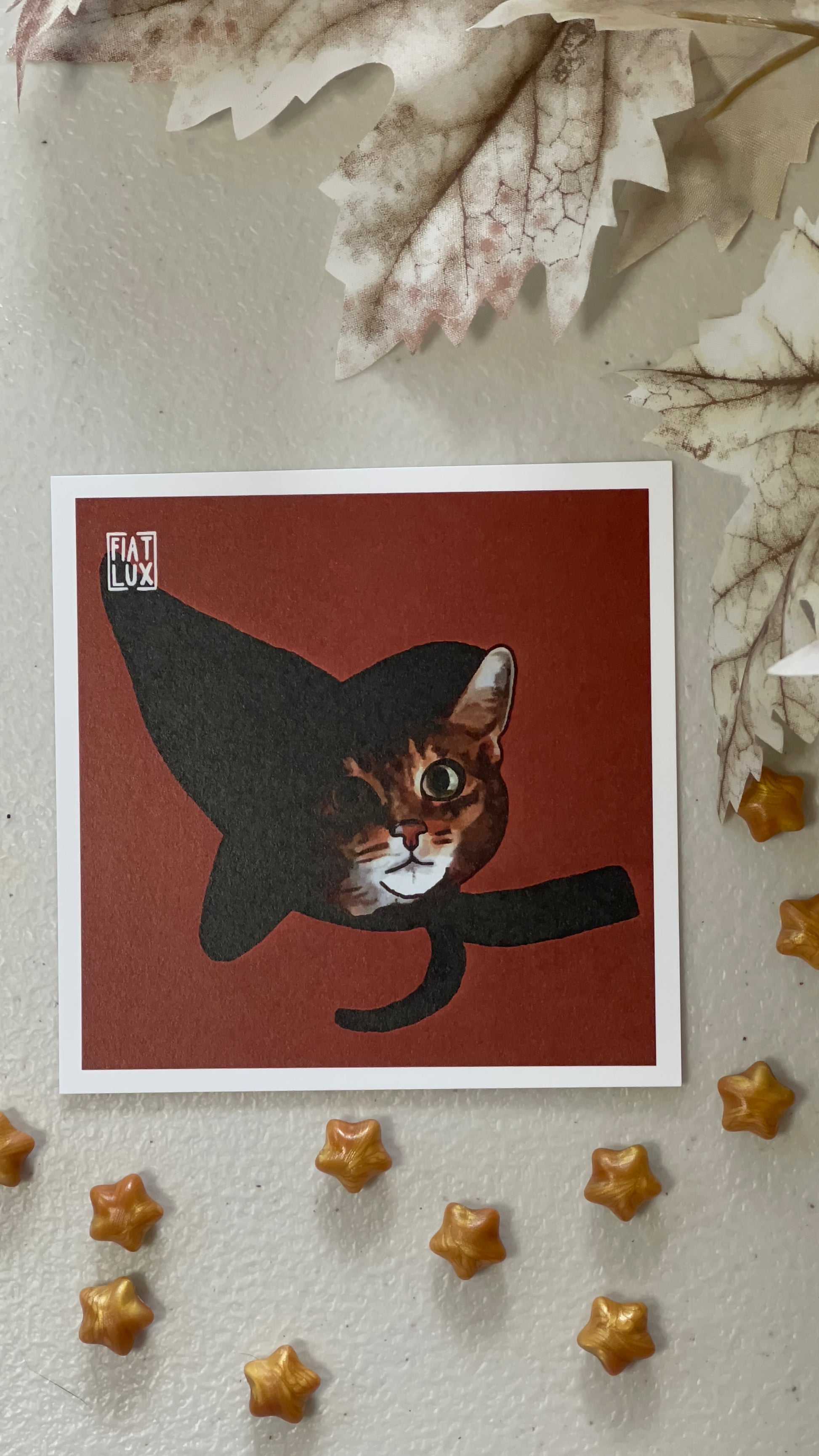 Art print of a dark orange tabby cat in a black witch hat on a solid orange background.