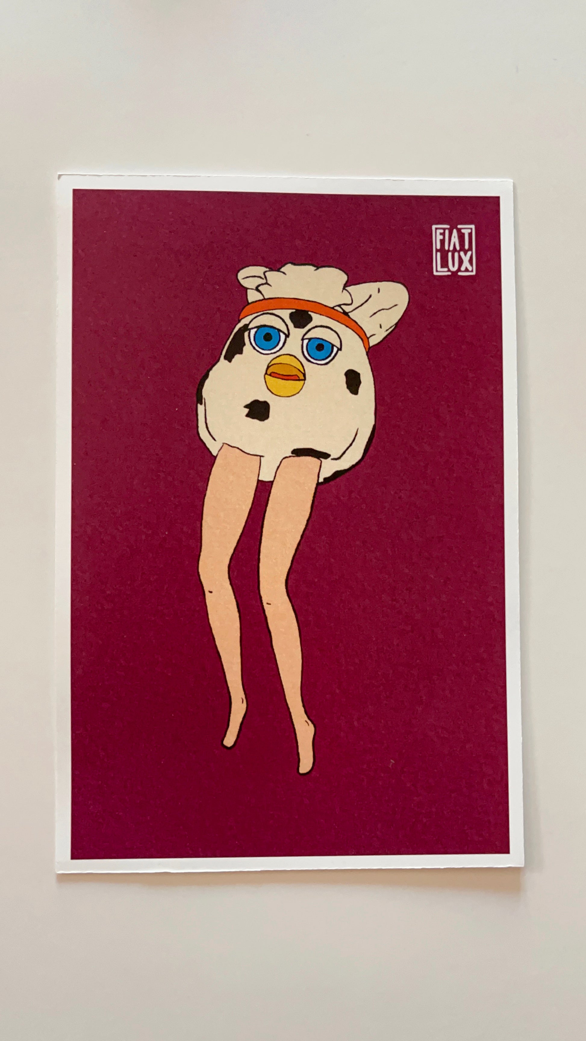 Art print of a furby modified with long doll legs on a solid burgandy background.