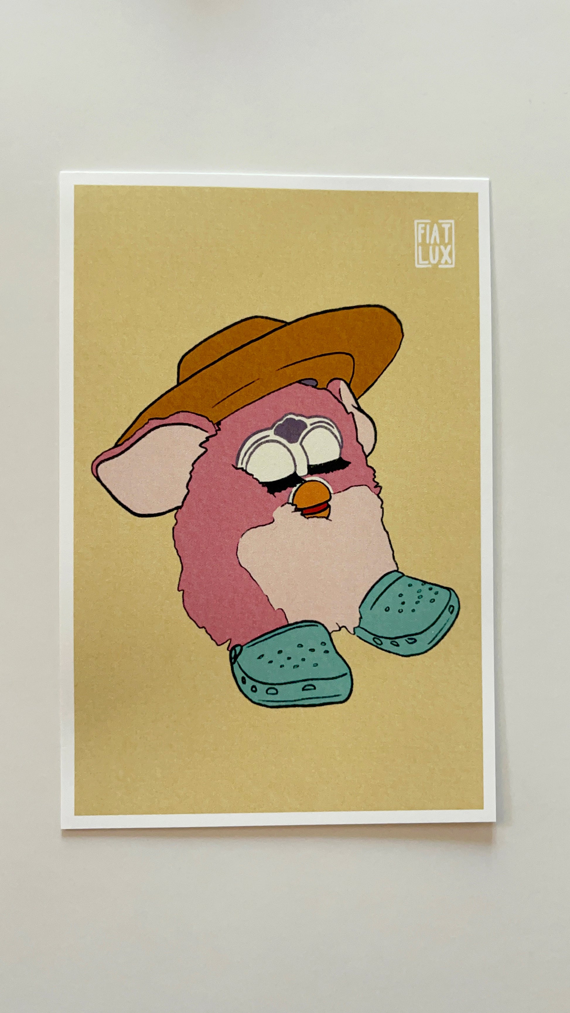 Art print of a furby in a yellow sun hat and teal crocs on a solid soft yellow background.