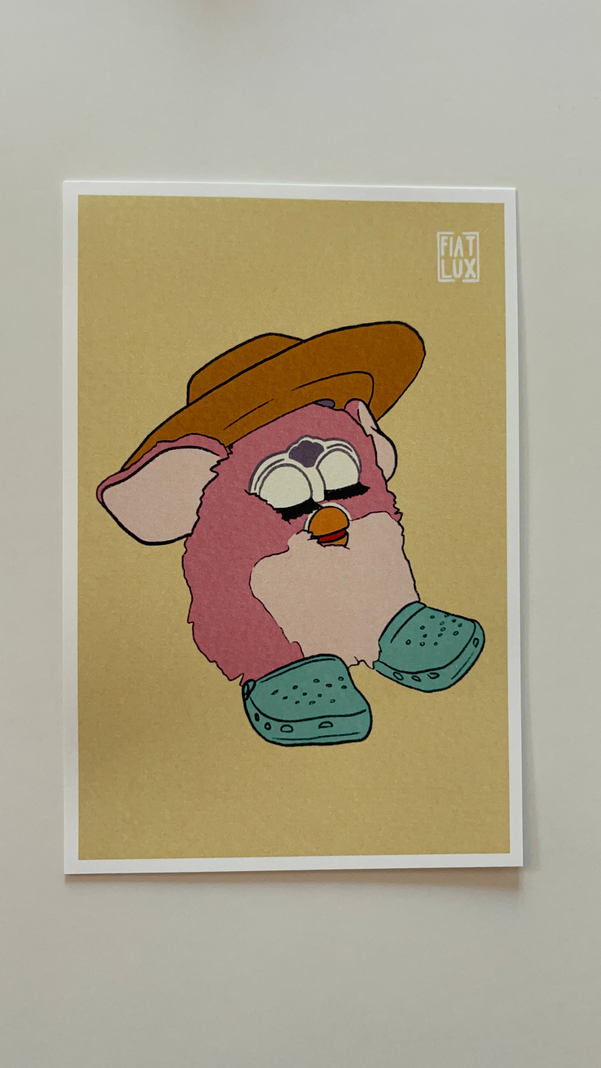 Art print of a furby in a yellow sun hat and teal crocs on a solid soft yellow background.