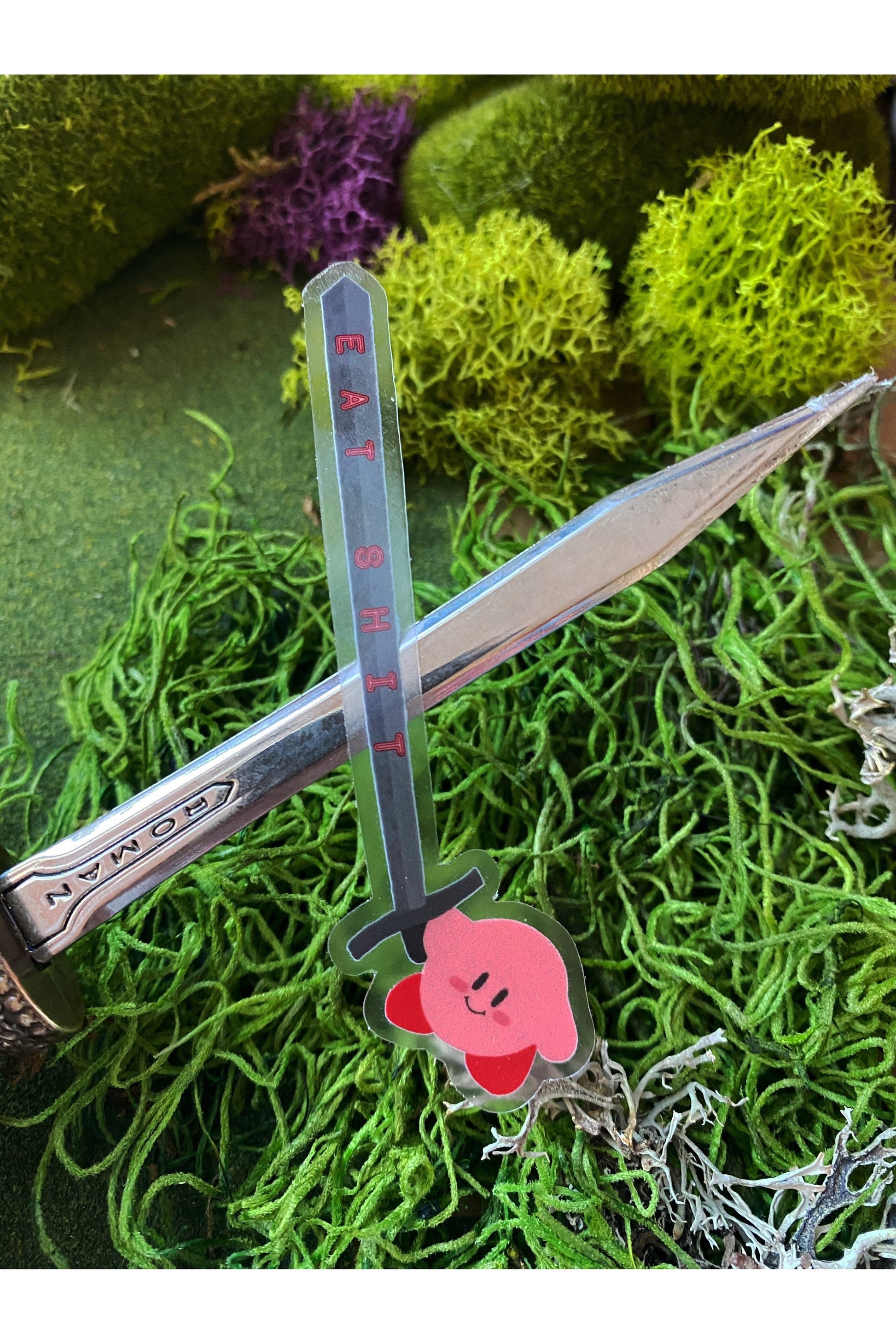 vinyl sticker of kirby holding a sword that reads eat shit in pink text down the blade