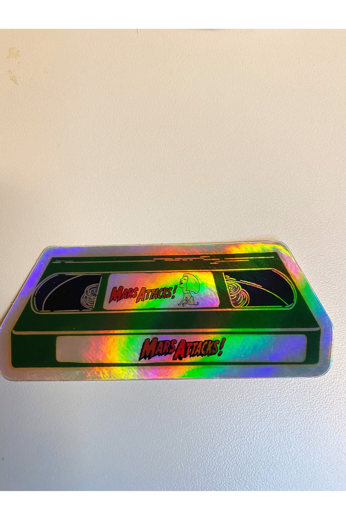 sticker of a green VHS tape of mars attacks! with green slime in holographic vinyl