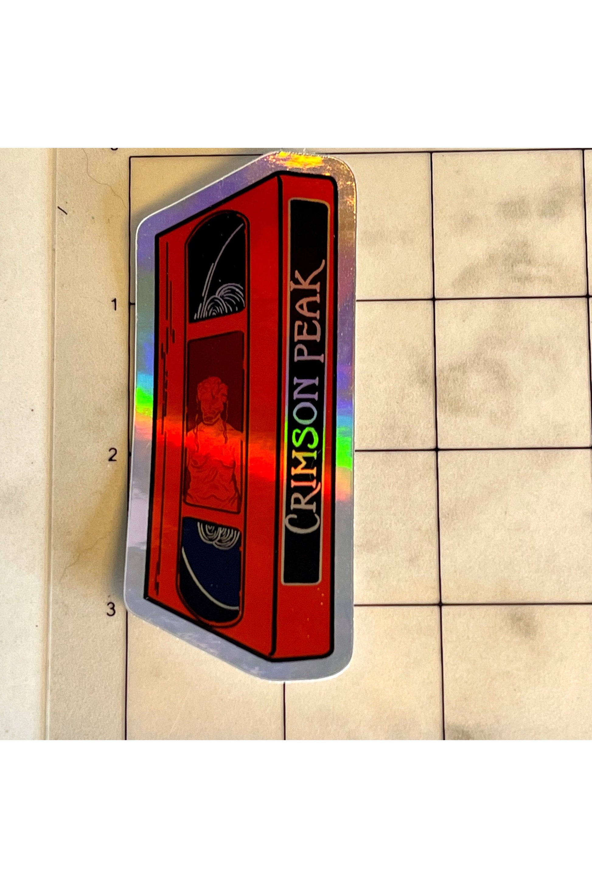 sticker of a red VHS tape of crimson peak in holographic vinyl